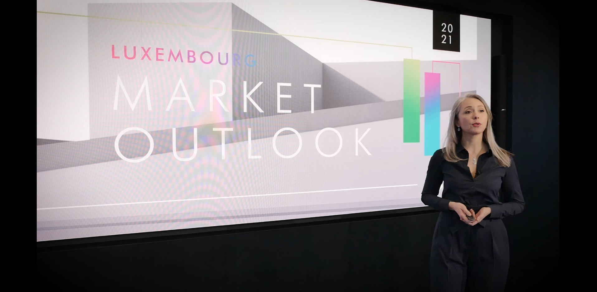 Kathia Robert parle du marché résidentiel luxembourgeois devant sa présentation affichée sur un grand écran LED lors du webinaire