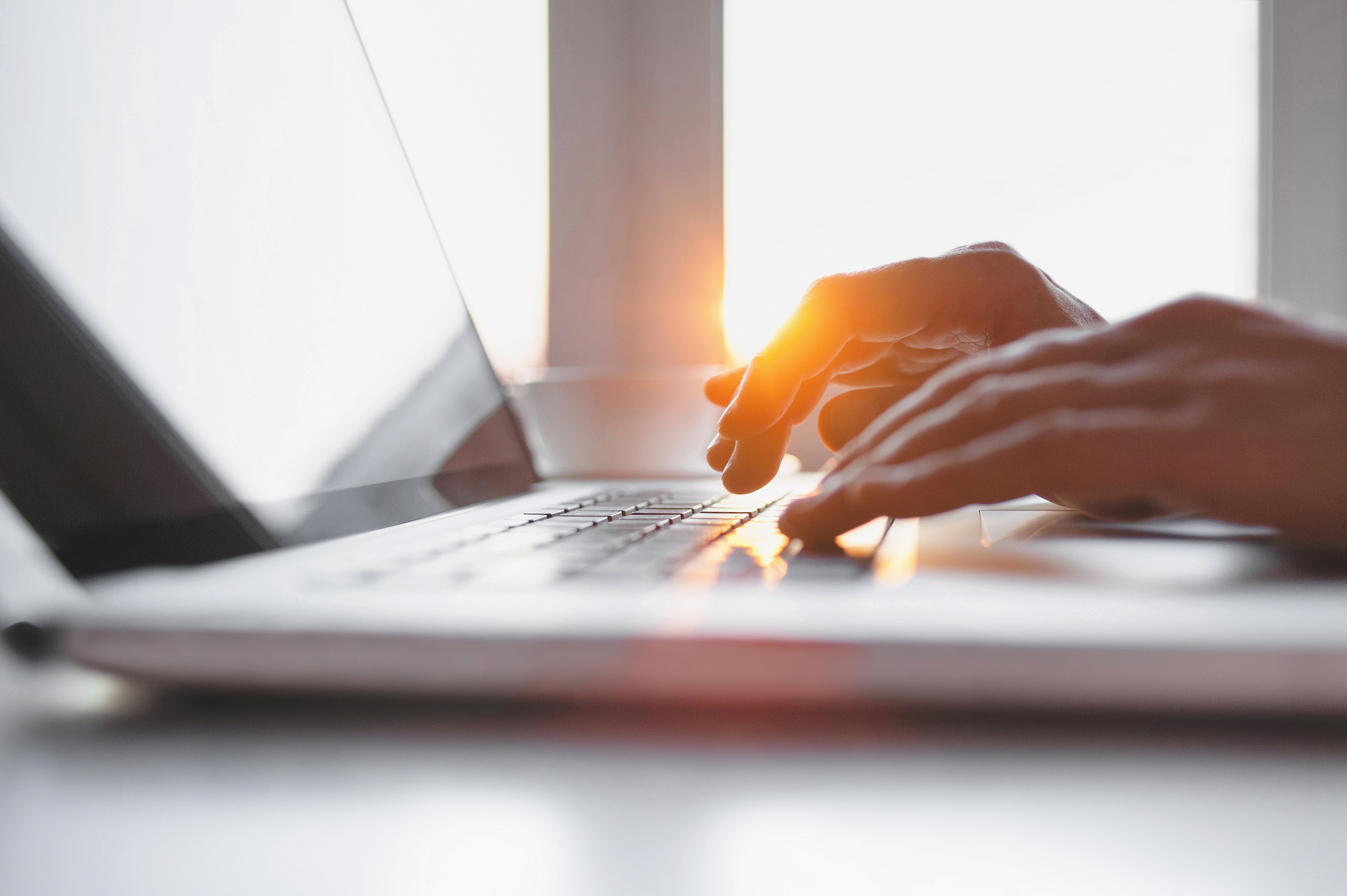 Close-up of male hands typing on laptop keyboard