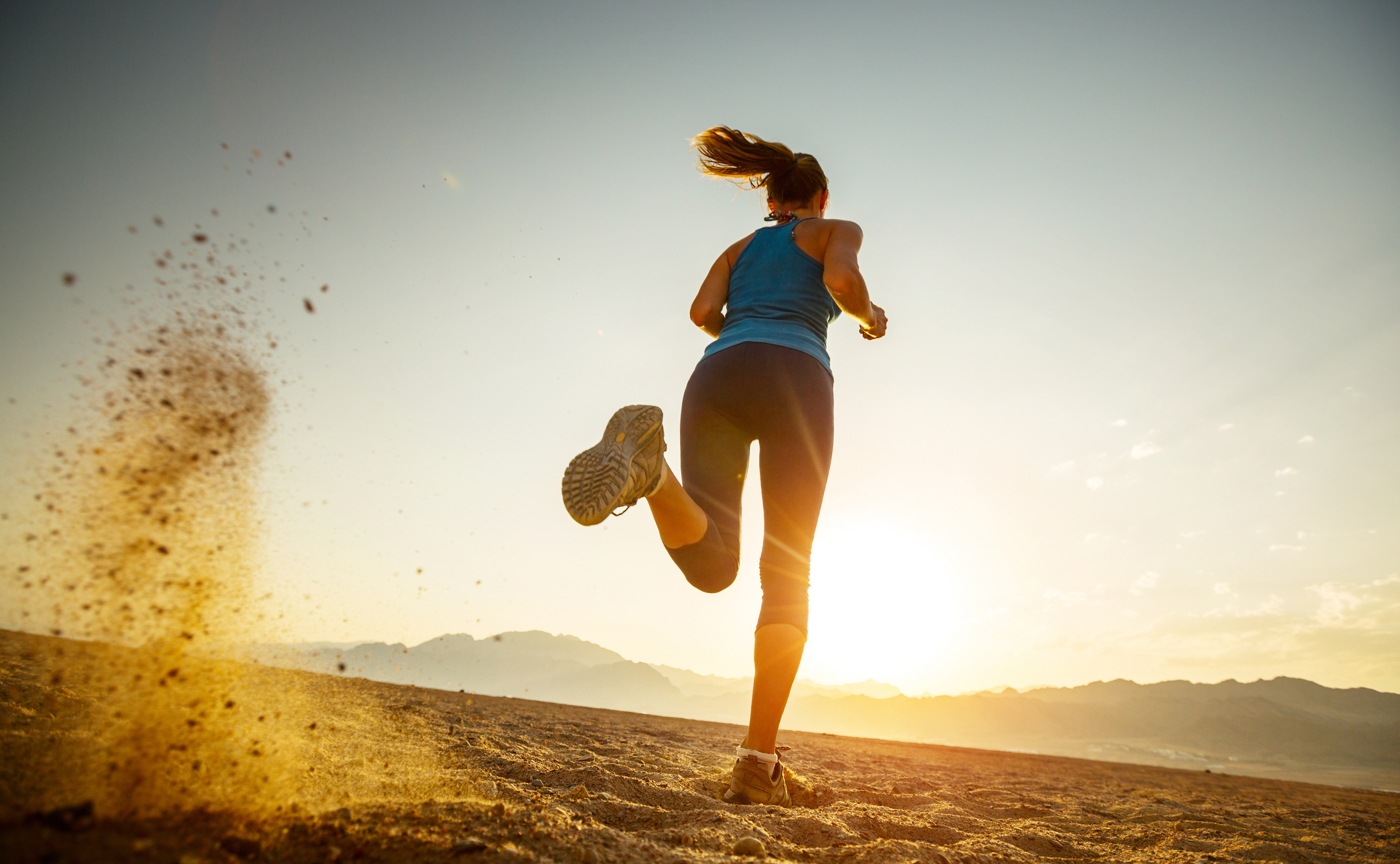 Young lady running in the desert at sunset
