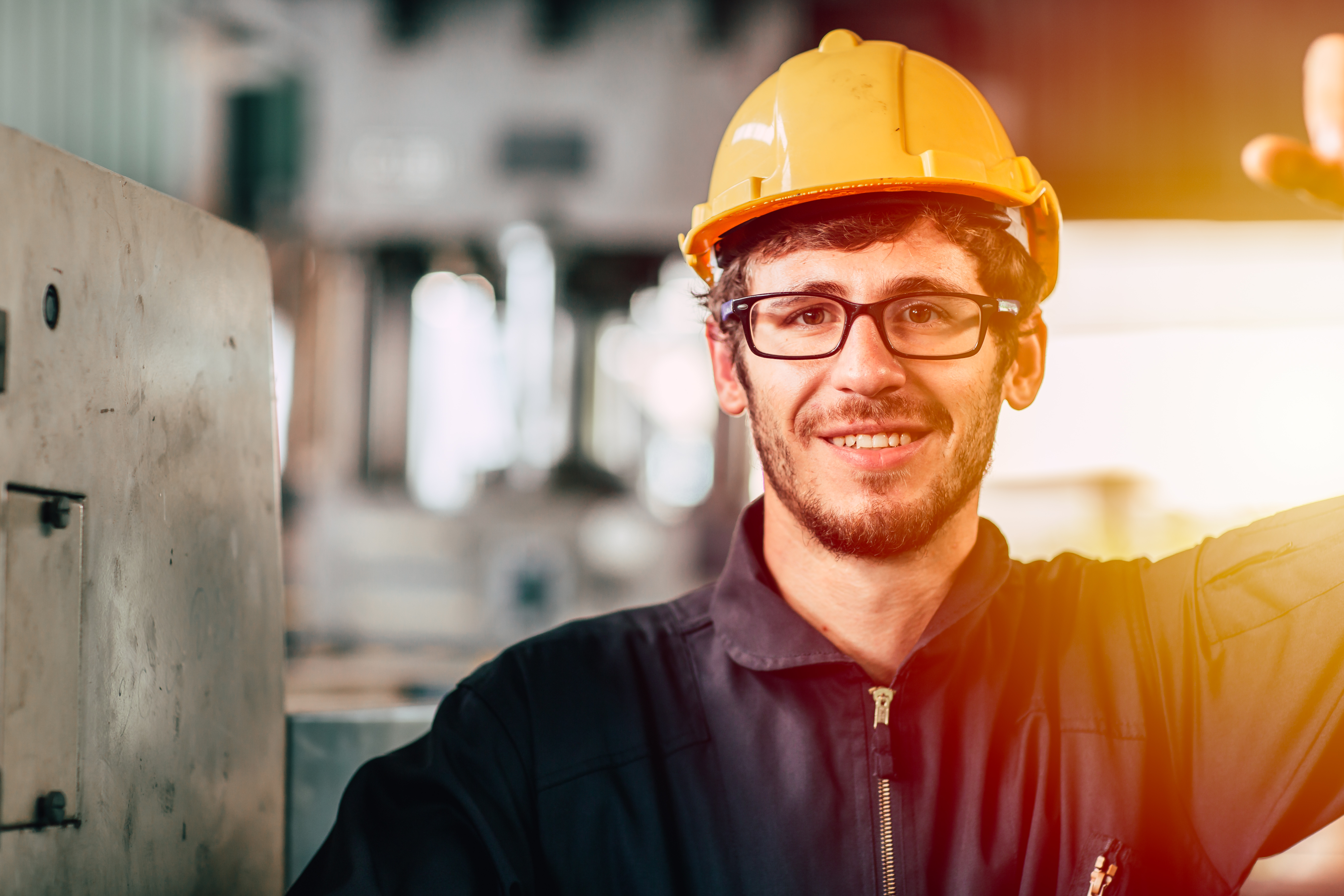 Closeup portrait happy worker nerdy glasses working in industry factory wearing safety suit cloth and yellow helmet.