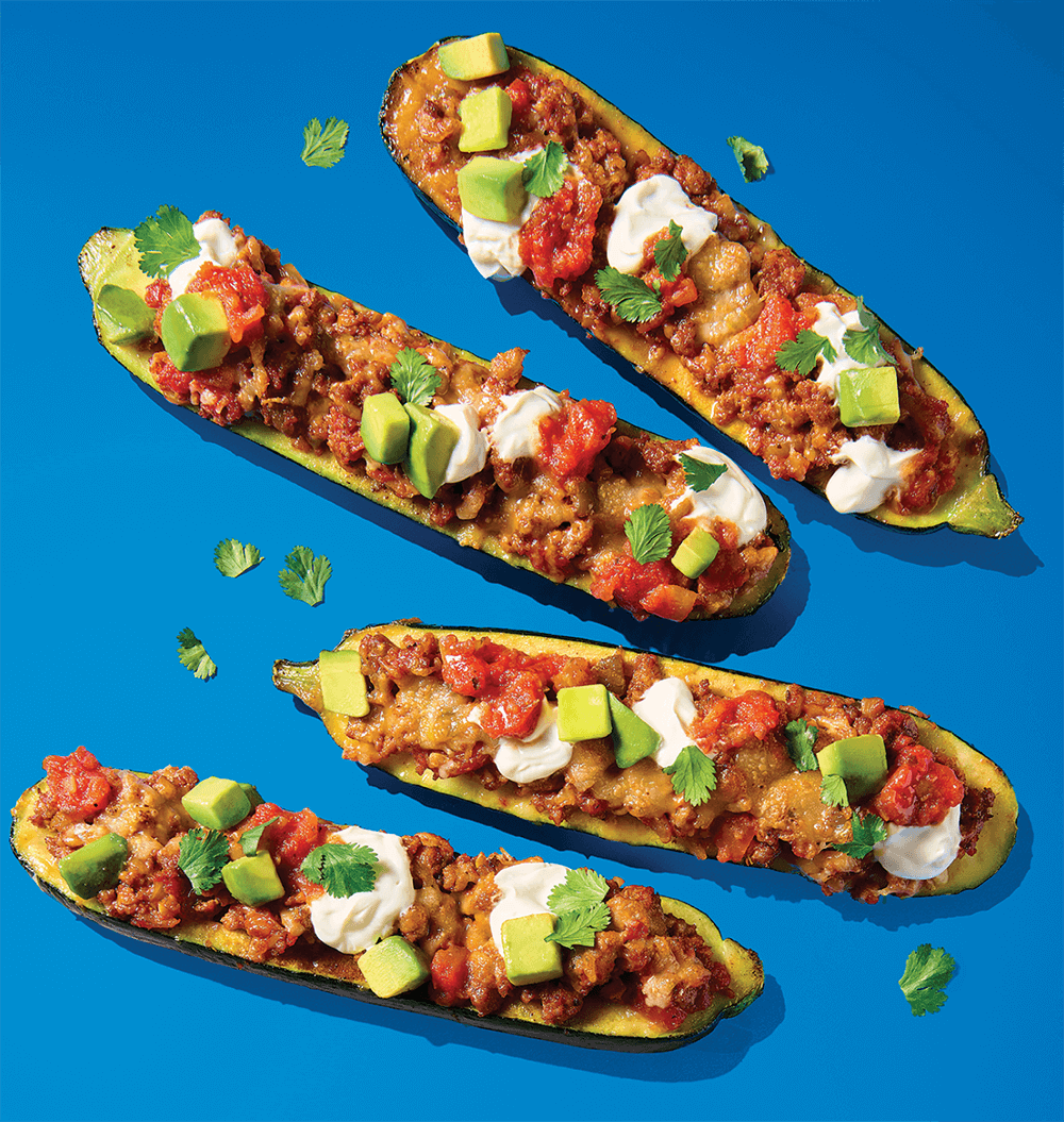 Group of 4 Zucchini Boats  with Scattered Cilantro over a Blue Background