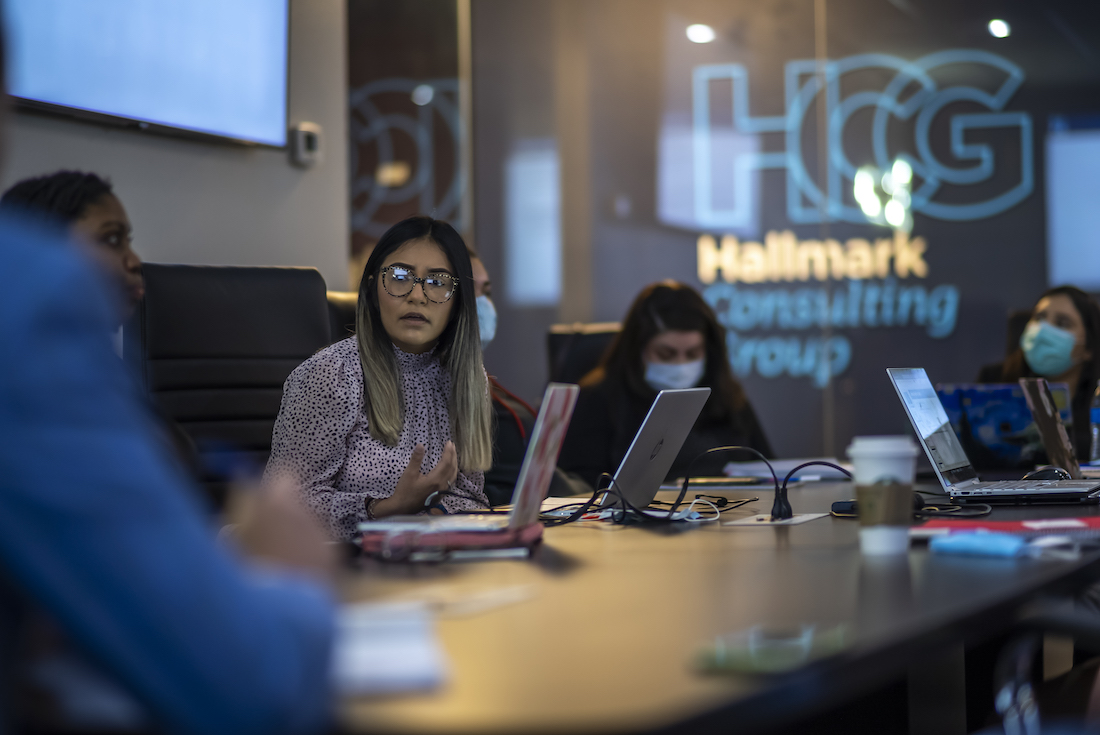 Attractive aged businesswoman, teacher or mentor coach speaking to young people, senior woman in glasses teaching audience at training seminar, female business leader speaker talking at meeting