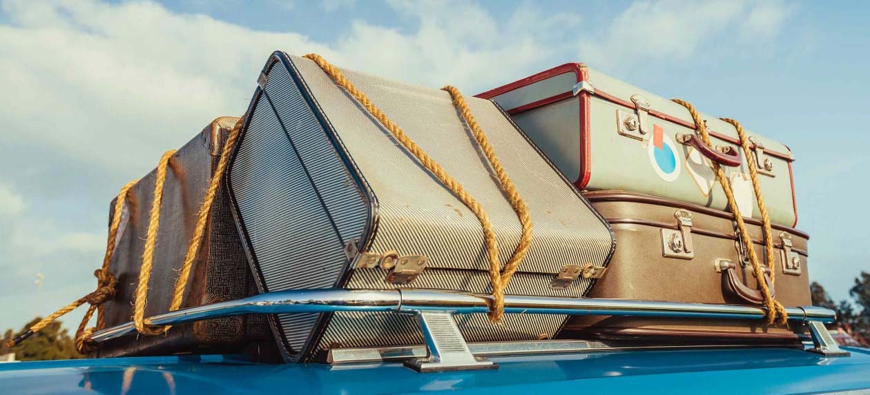 Suitcases tied to top of a car
