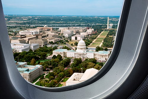 The view from within a commercial airplane window flying over government buildings of Washington D.C.