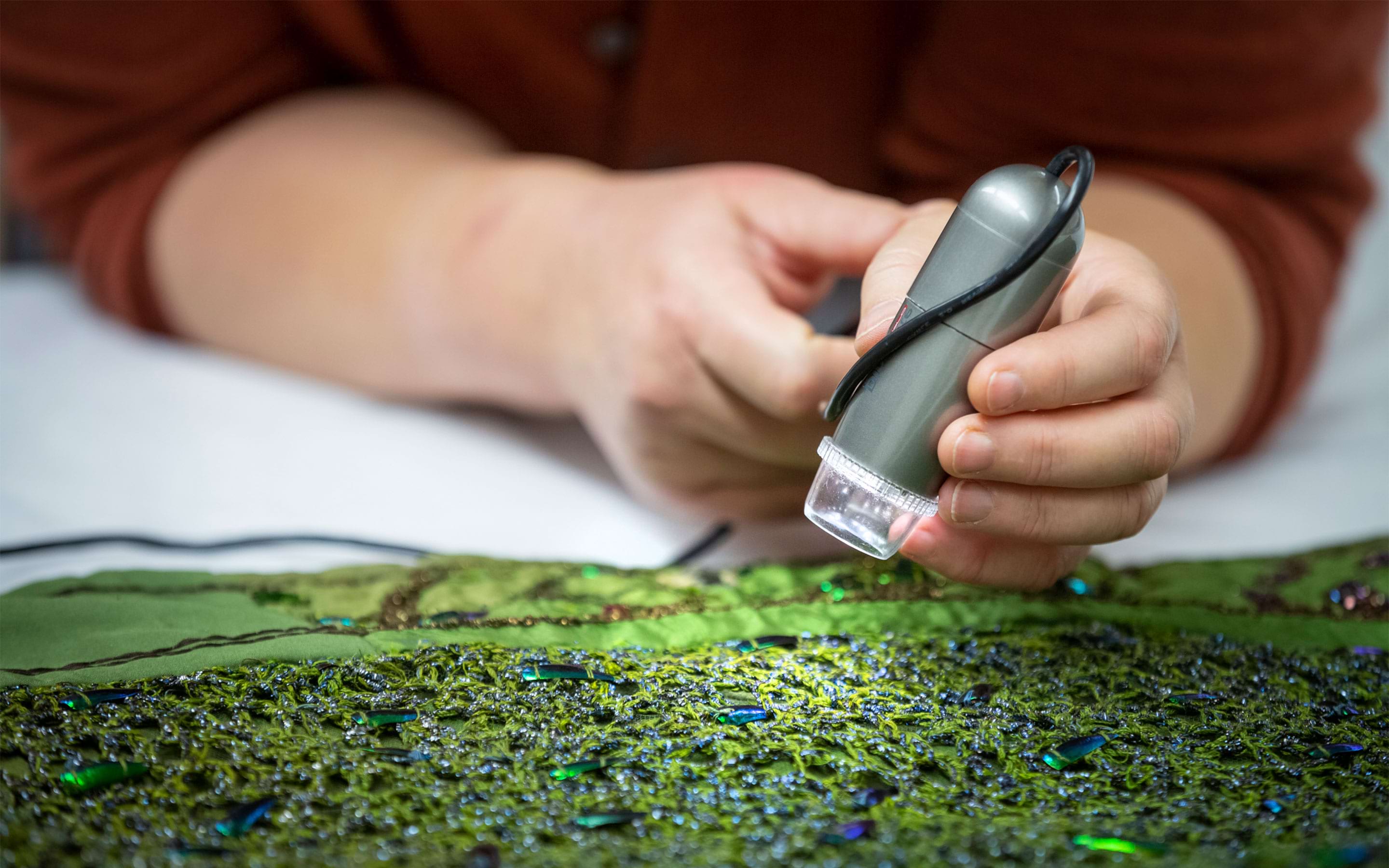 Using a digital microscope to inspect the Beetlewing dress (CMS 1118839.1) from Smallhythe Place at the Textile Conservation Studio, Norfolk