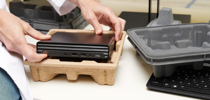Hands pulling HP electronic out of molded fiber packaging